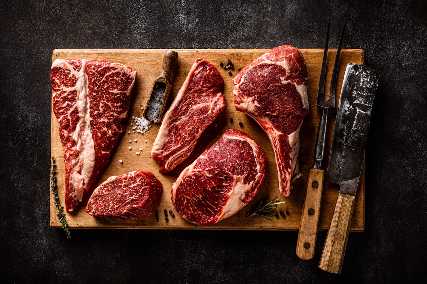 Cuts of fresh red meat resting on a wooden board.